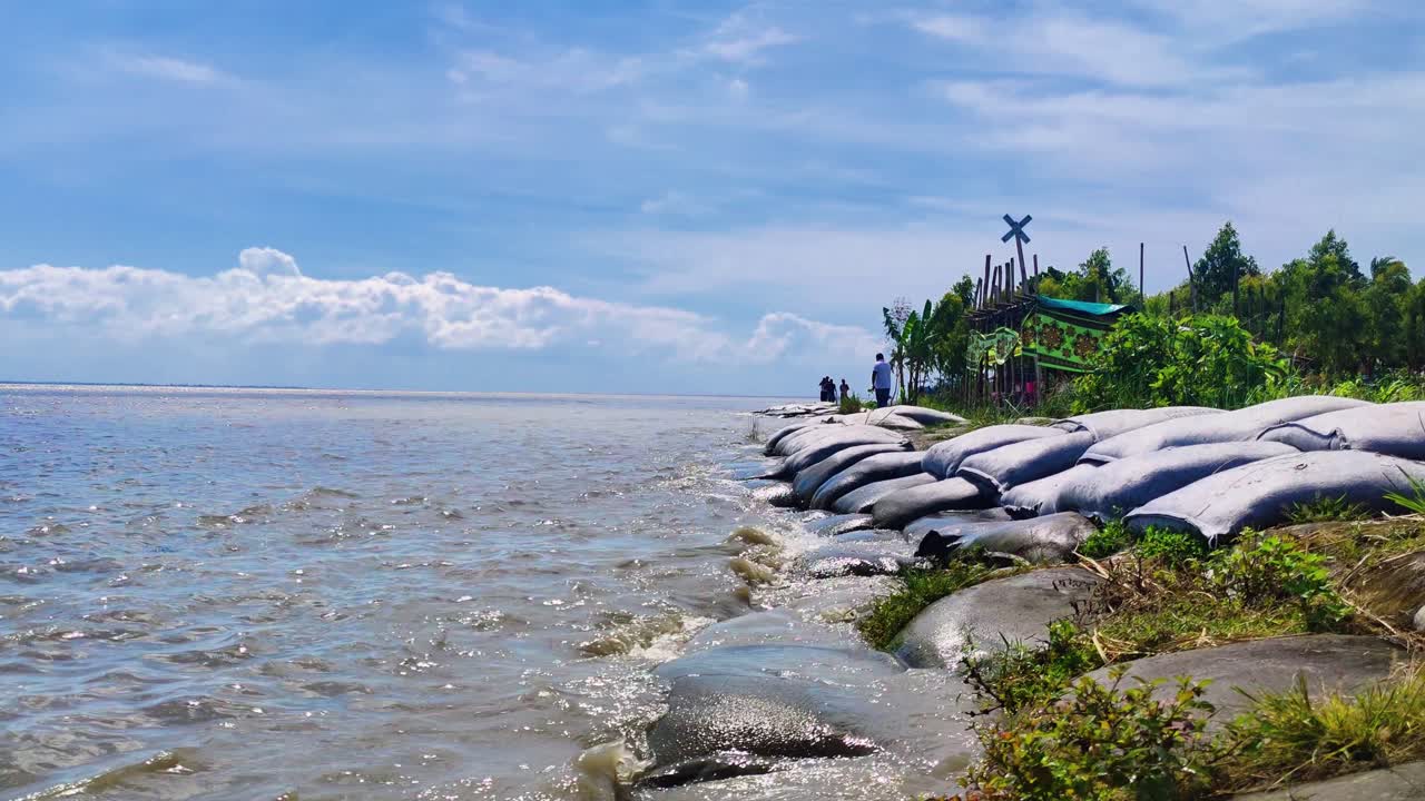 Waves washing against flood embankment with sandbags laying along India's coastline, Climate change