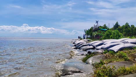 Waves-washing-against-flood-embankment-with-sandbags-laying-along-India's-coastline,-Climate-change