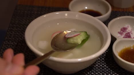 dongchimi korean radish water kimchi, showing on spoon close-up in restaurant