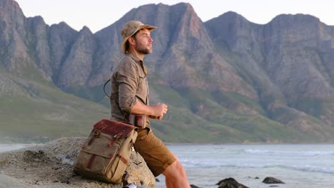 a man in a safari hat makes a photo at the ocean sunset cape town africa