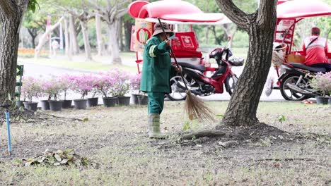 worker sweeping leaves near parked motorcycles.