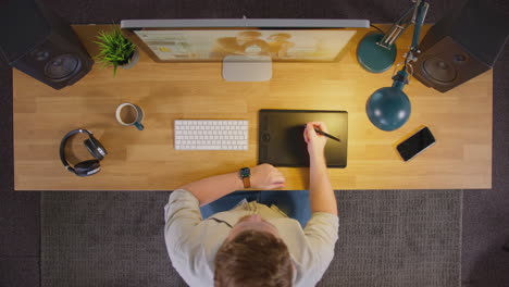 Vista-Aérea-De-Un-Diseñador-Gráfico-Masculino-Trabajando-En-La-Pantalla-De-Una-Computadora-En-Una-Oficina-Creativa-Por-La-Noche