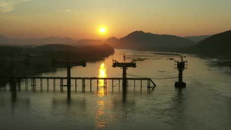 sunrise over river bridge construction