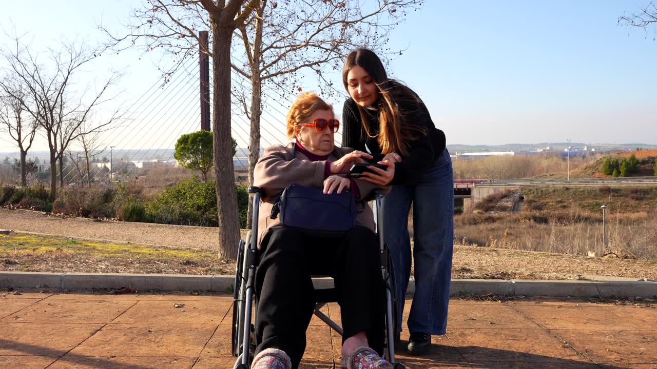 Granddaughter and grandmother take and review selfie together in park