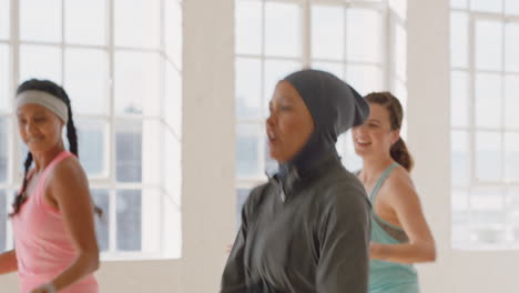 Glückliche-Muslimische-Frau-Tanzt-Gruppe-Gesunder-Menschen,-Die-Das-Training-Genießen-Und-Choreografie-Tanzbewegungen-üben-Und-Spaß-Im-Fitnessstudio-Haben
