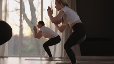 a group of women is engaged in stretching and balance with an instructor in a beautiful hall with large windows. healthy lifestyle group classes