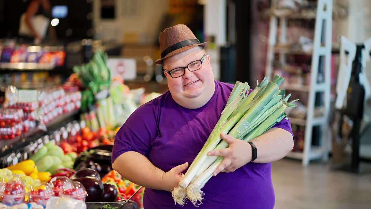 retrato de un hombre feliz con sobrepeso en una camiseta púrpura y un sombrero marrón y gafas que sostiene un ramo de chalotes en sus manos y posa contra el fondo de un gran supermercado