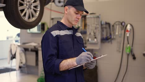 mecánico en un taller de reparación de automóviles haciendo notas en su tableta