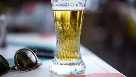 Bubbling-sharp-beer-at-table-with-glasses-next-to-it,-slow-motion