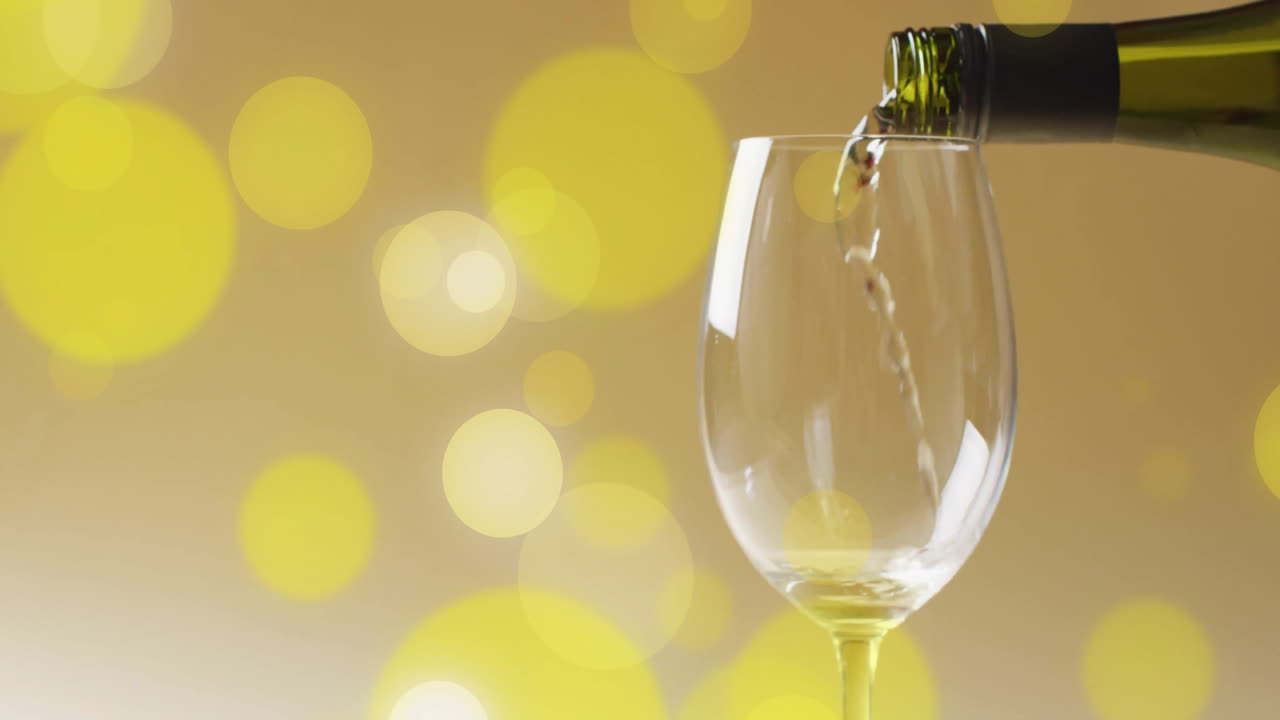 Composizione di vino bianco versato in un bicchiere su macchie gialle.
