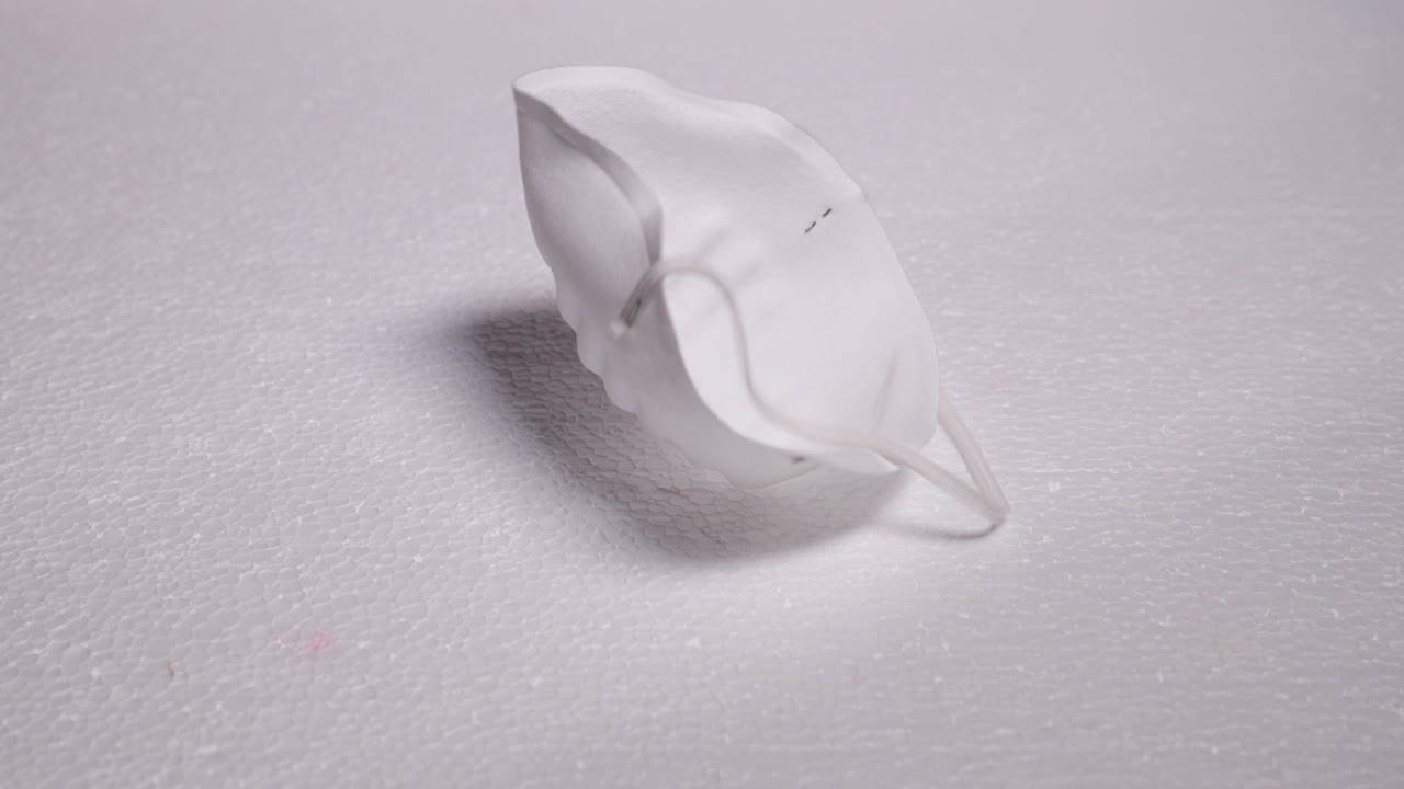 Falling protective white mask mask against threats like corona covid-19 virus on white substrate that protects mouth and nose on plate capture in 4k 60fps