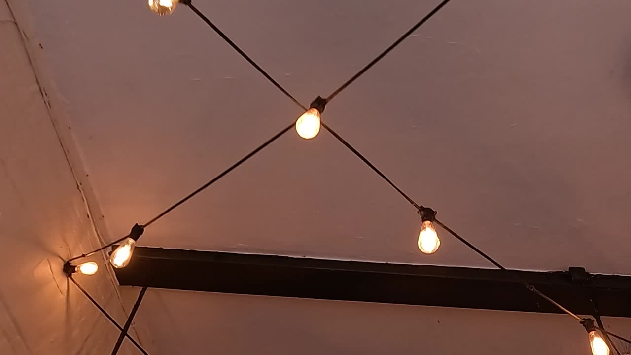 Warm string lights and a lantern hang from ceiling beams, creating a cozy atmosphere.