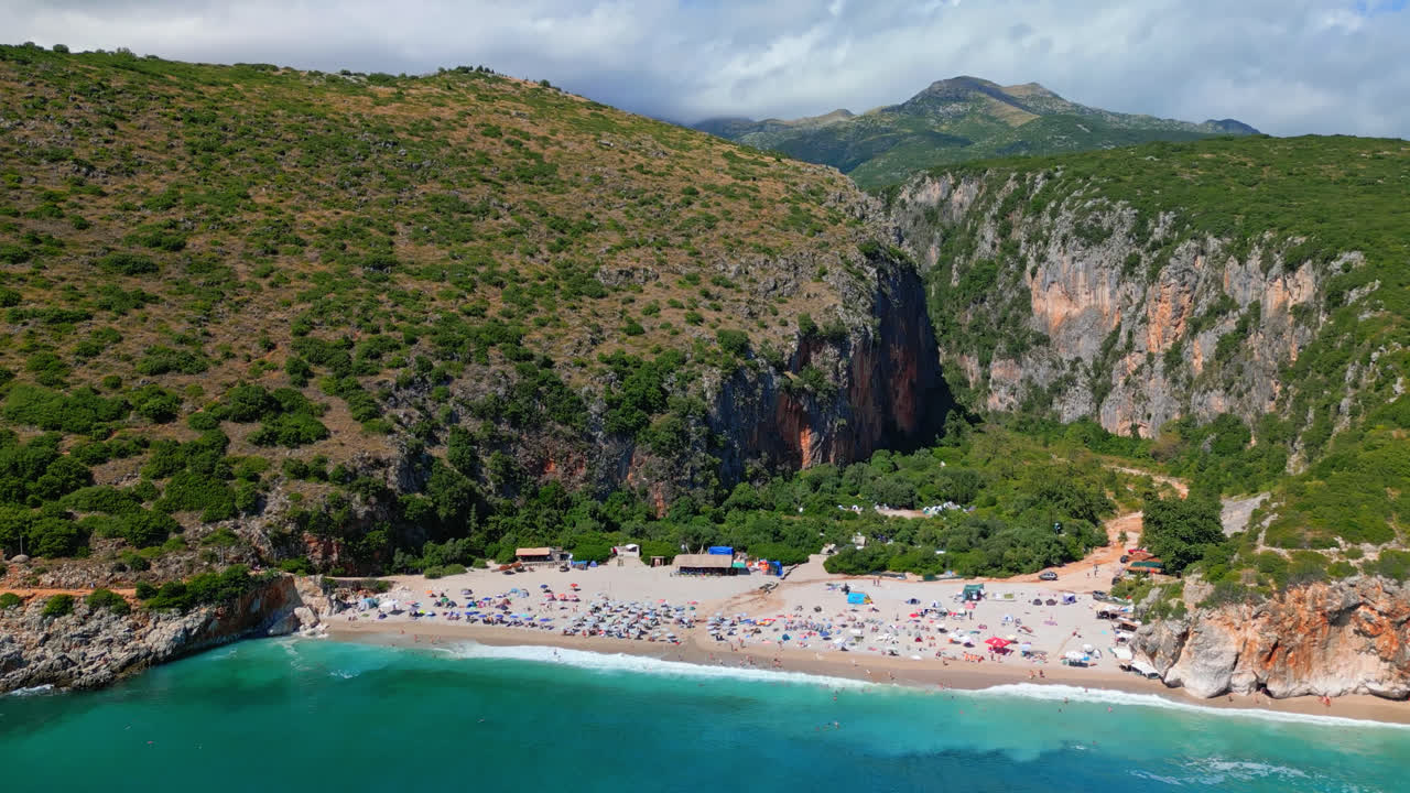 Aerial drone tilt up shot of turquoise water of Ionian sea in secluded Gjipe beach, Albania on a sunny day