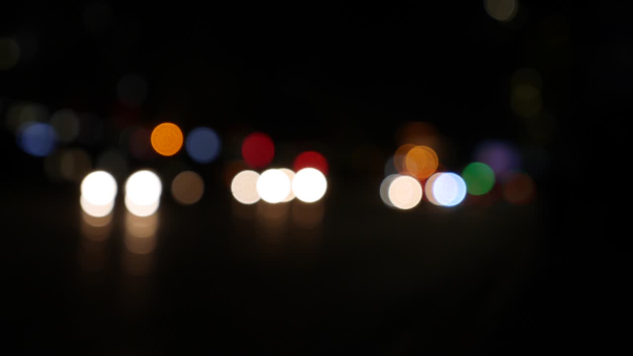 hermoso bokeh brillante en el fondo oscuro borroso por la noche. el redondo bokeh colorido brilla de las luces de los coches en la calle de la ciudad. fuera de foco con borroso. luces de la ciudad sin enfoque. bokeh de tráfico. concepto abstracto