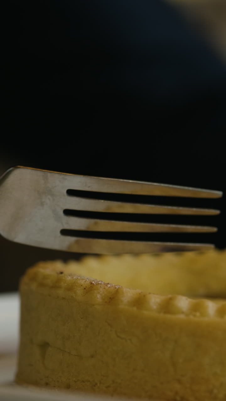 Close-up of a slice of pie being eaten with a fork, showing the smooth, golden texture of the dessert, with a blackberry filling