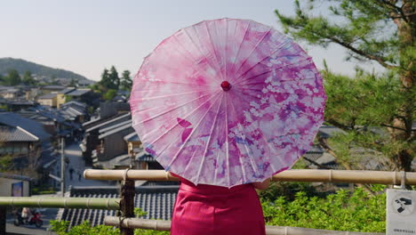 woman with wagasa umbrella stand at viewpoint near yasaka pagoda in kyoto, japan