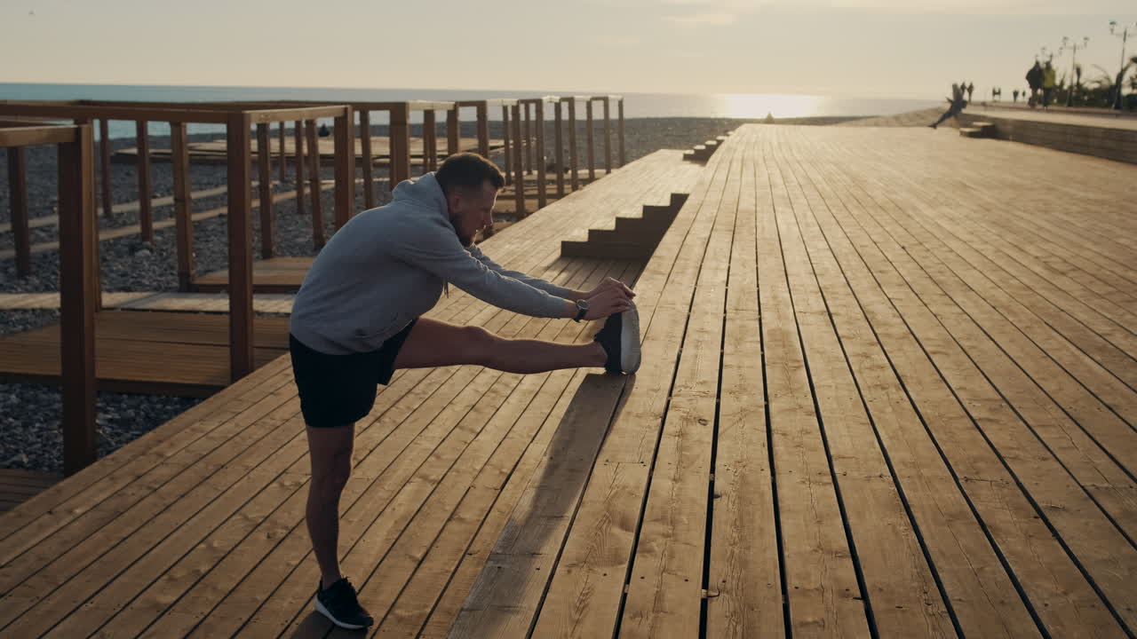 Man Stretching on a Wooden Beach Deck at Sunset