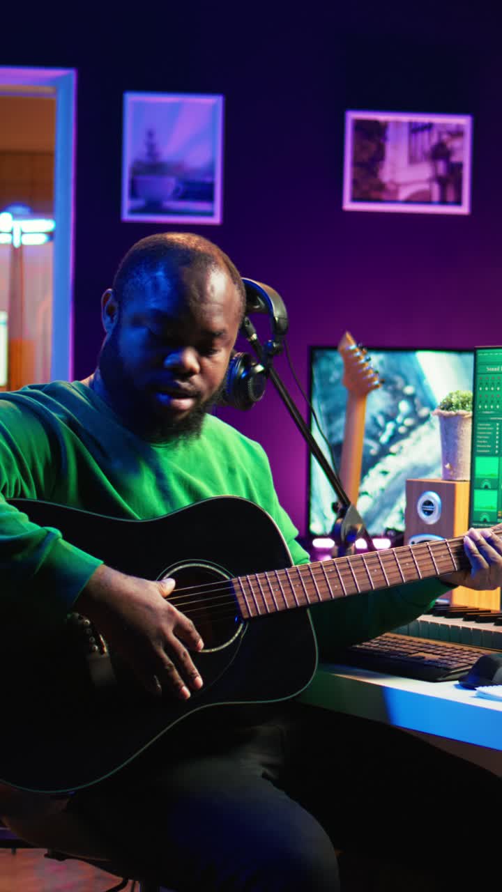Afroamerikansk mand spiller akustisk guitar i hjemmestudie