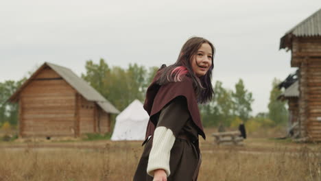 Young-woman-in-medieval-clothes-runs-towards-wooden-houses