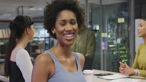 Portrait-of-happy-african-american-businesswoman-over-diverse-business-colleagues-discussing