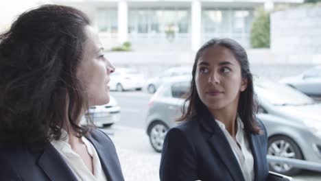 dolly shot of two serious business colleagues walking on city street, talking and discussing work projects