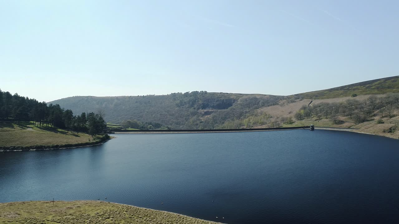 toma aérea panorámica a la izquierda con gansos en el agua del embalse de kinder que muestra el muro de la presa y las colinas en el otro lado