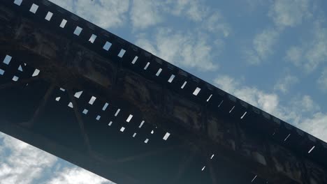 tight shot of the pope lick railroad trestle in louisville kentucky from below, with the clouds passing by against a blue sky above