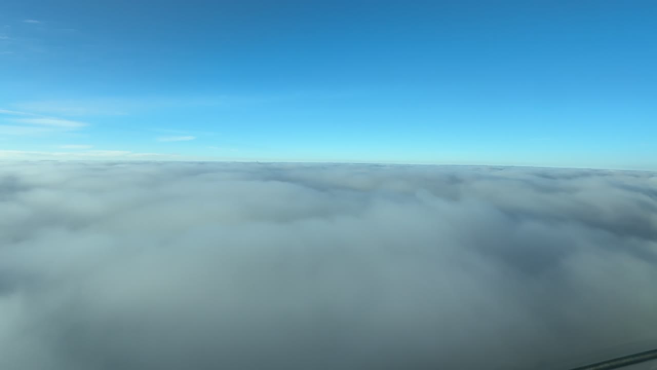 POV taken from a jet cockpit while flying just above an endless sea of ethereal stratus clouds under. a bright blue sky