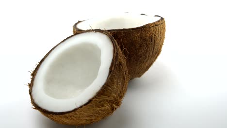 coco tropical maduro dividido en dos mitades girando sobre un fondo blanco. frutas exóticas en bucle