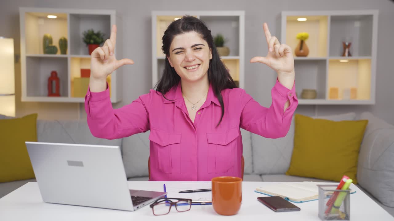 la mujer que trabaja en la oficina hace el símbolo del corazón mirando a la cámara.