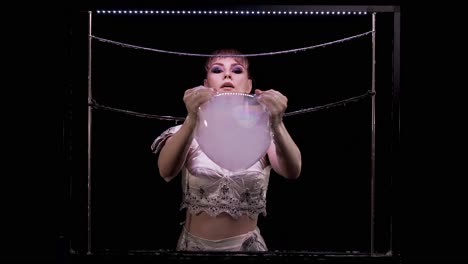 young girl does tricks with soap bubbles she takes with her hands a big bubble with smoke inside and pierces it