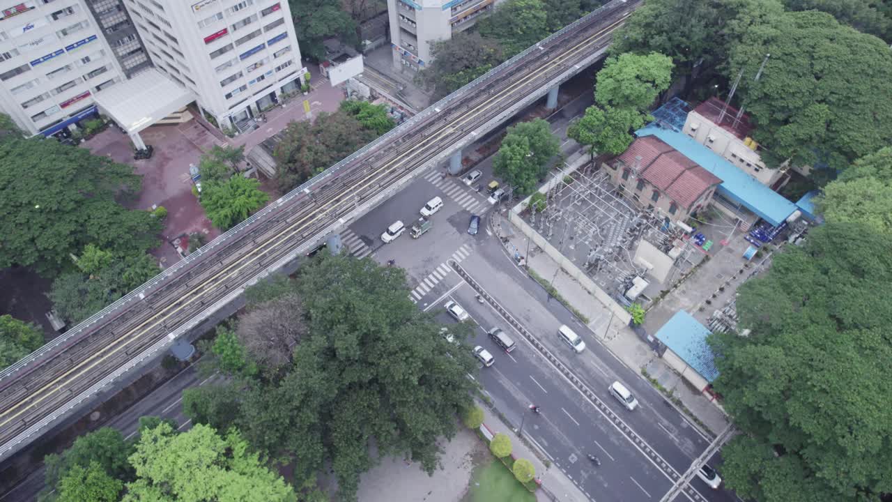 A view of a rooftop terrace and a metro train track from an office building Inside those buildings, a cloudy day's aerial view of Bangalore city shows a single intersection