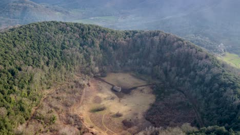 Círculo-Lento-Aéreo-Alrededor-Del-Volcán-Inactivo-Santa-Margarita:-Enorme-Cráter-Y-Capilla-Histórica-En-Cataluña,-España