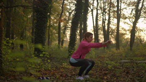 woman doing squats exercise in an autumn forest