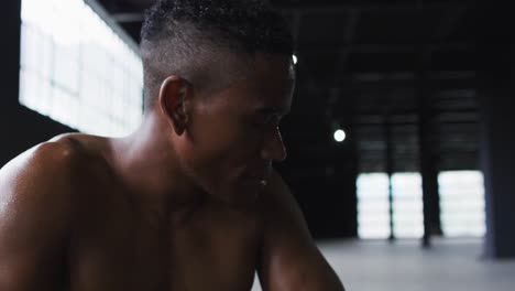 portrait of african american man resting after battling ropes in an empty urban building