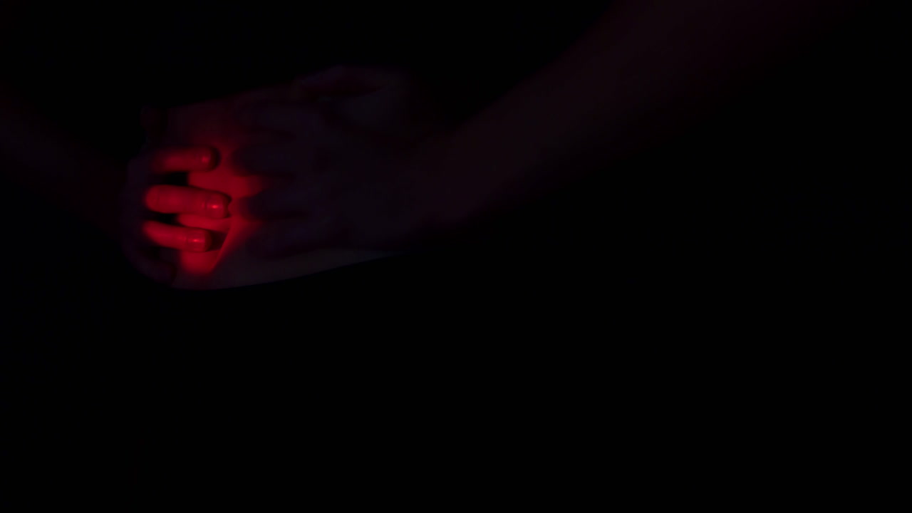 Abdominal pain. Close up of a woman's belly in the dark. A red light appears on the abdomen, suggesting an impending contraction. The woman crouches and grabs her belly with her hands