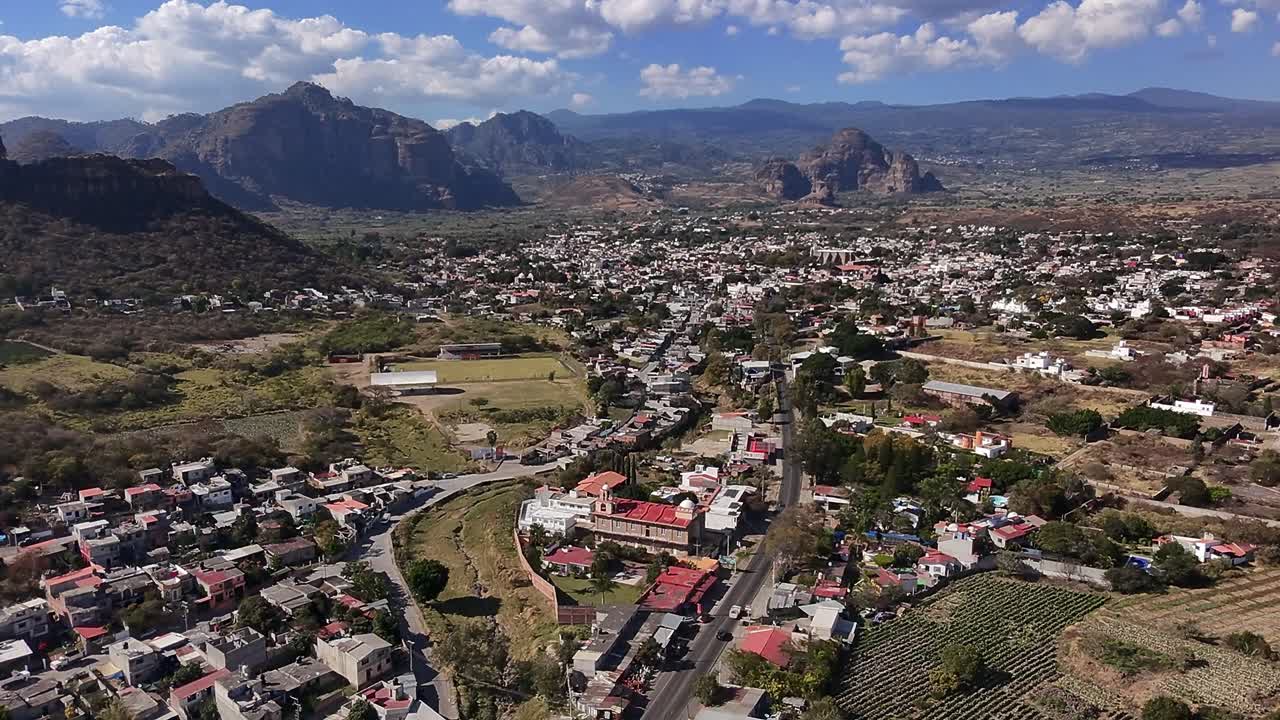 Aerial: Oaxtepec cityscape with blue cloudy sky and mountains during the day in Morelos, Mexico, establishing drone shot