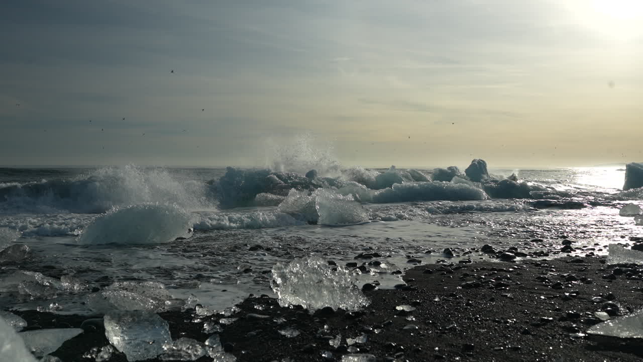 Slow motion shot of ice blocks and ocean waves at Black Diamond Beach in Iceland