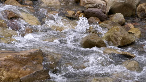 clear stream running through stone boulders abundant river flowing in slow motion