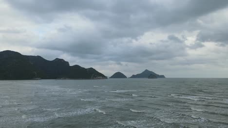 Imágenes-Aéreas-Hacia-Estas-Islas-Y-Montañas-Que-Revelan-Olas-Y-El-Oscuro-Cielo-Matutino-Con-Nubes-De-Lluvia