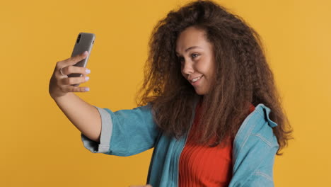 caucasian curly haired woman taking selfies on smartphone.