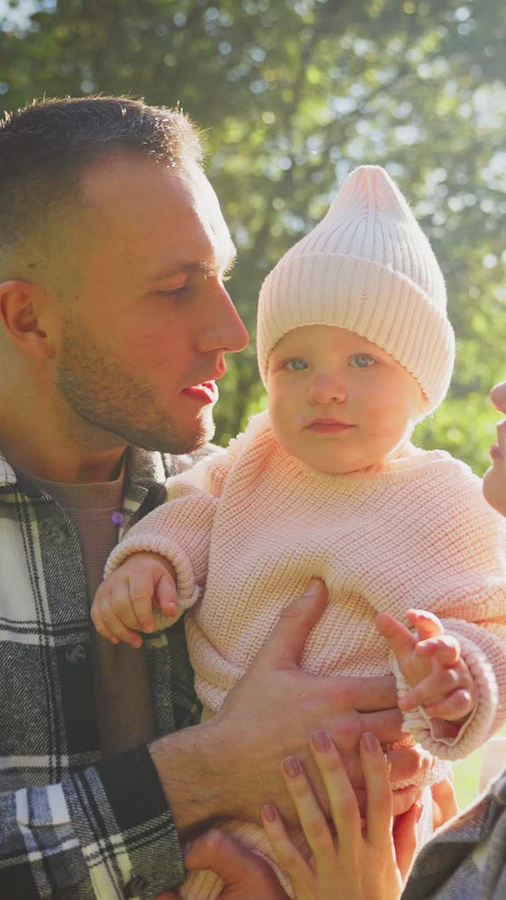 Loving Parents Kissing Their Baby's Cheeks Outdoors