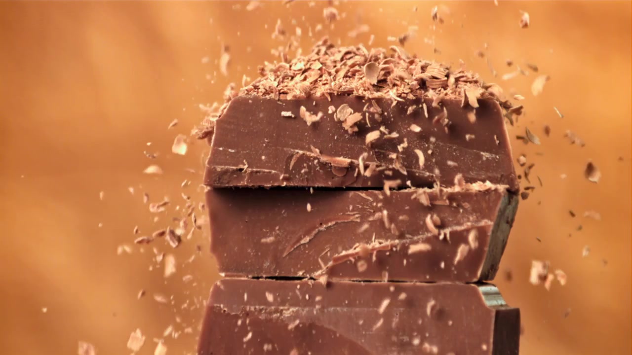 Slowmotion af chokoladespåner, der falder på stablede chokoladestykker