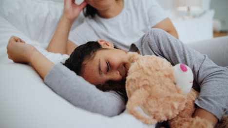 hija durmiendo en la cama con la madre y el oso de peluche