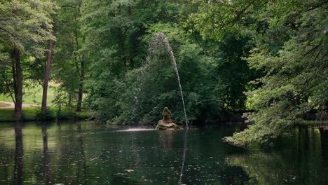 Ein-Brunnen-Im-Teich-Mit-Einer-Steinstatue-In-Der-Mitte-Versorgt-Im-Heißen-Sommer-Das-Wasser-Mit-Sauerstoff-Für-Die-Hier-Lebenden-Tiere