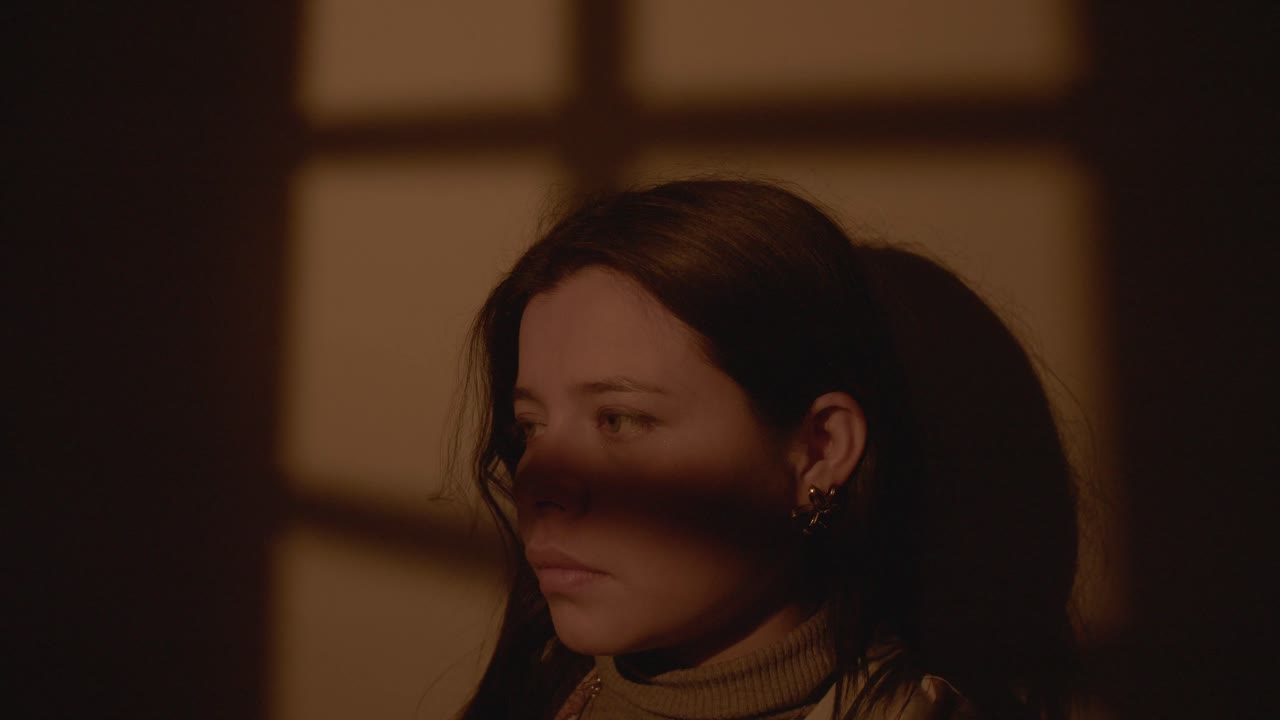 A woman looking thoughtful, framed by dramatic shadow play