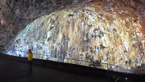 man walking in front of wall of solidified lava inside algar do carvao