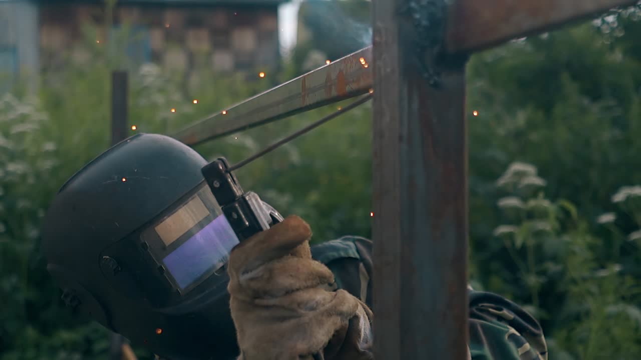 느린 동작 하드맨은 용접을 멈추고 마스크를 벗습니다.