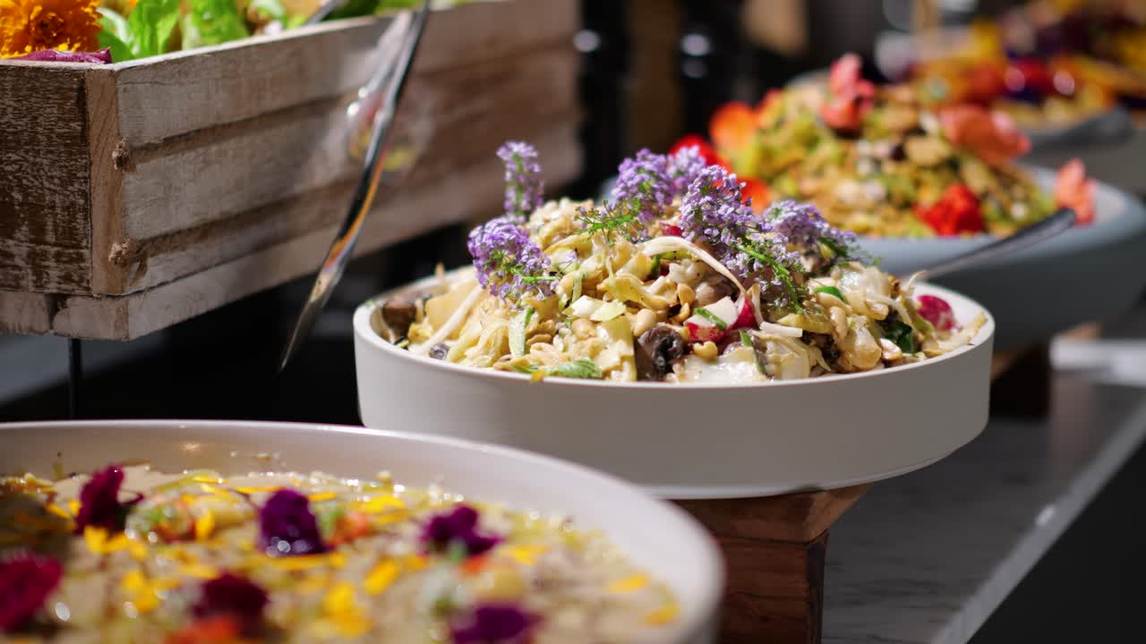 Beautifully presented gourmet salads with fresh ingredients and edible flowers at a buffet.