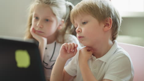 toddler boy and schoolgirl watch online lesson on laptop